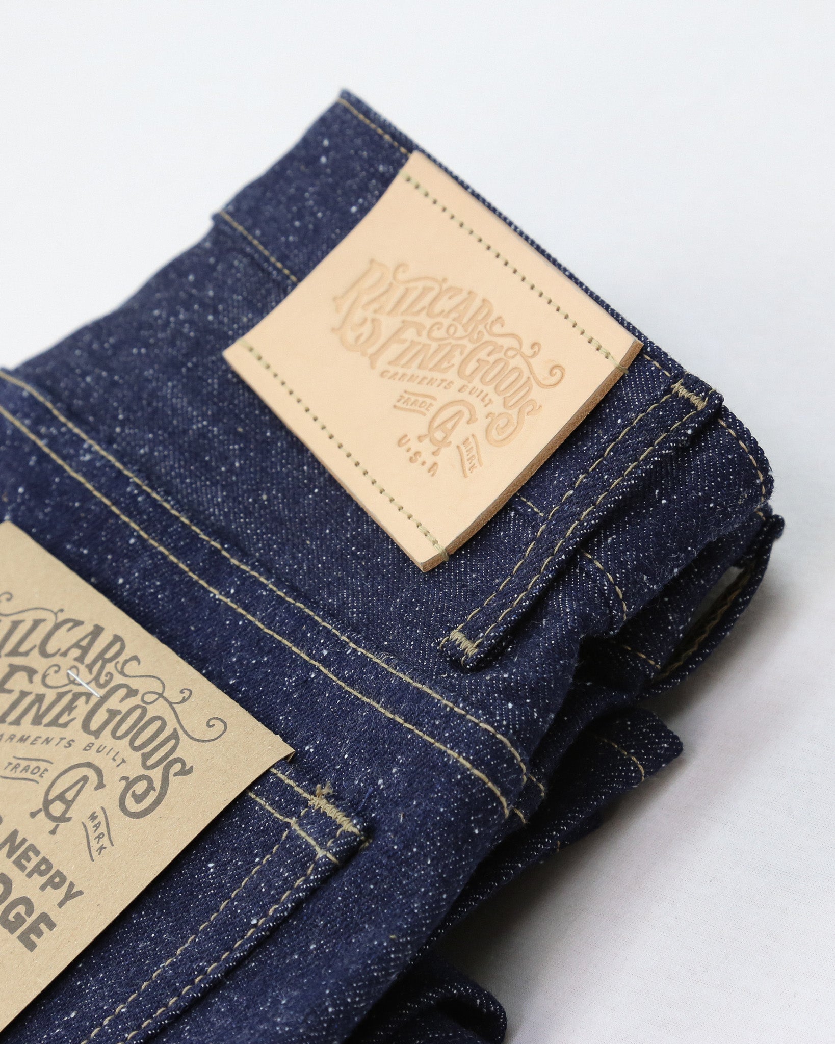 Folded denim jeans with a brand label on a white background