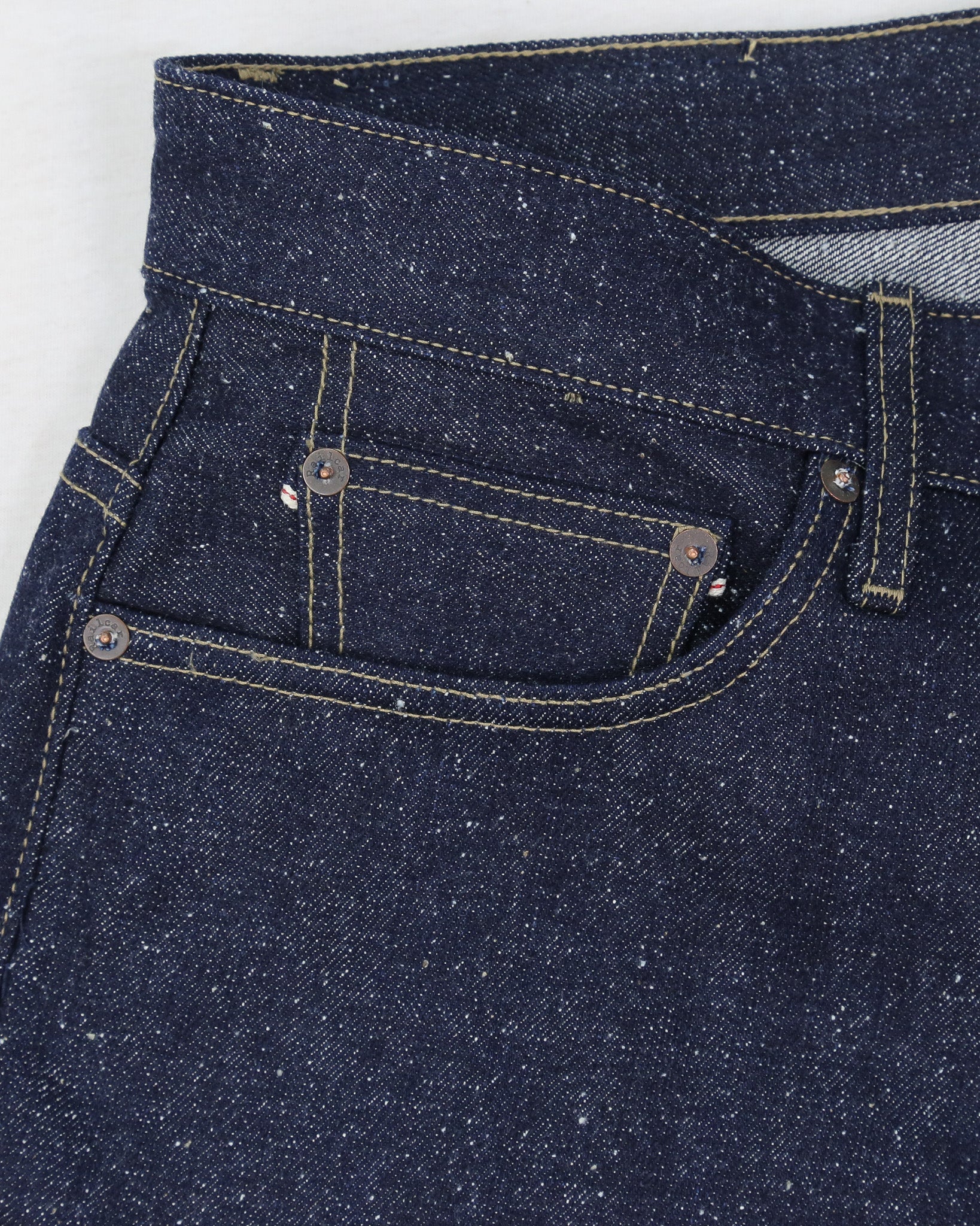 Close-up of X125 Super Nep denim jeans with stitching details on a white background