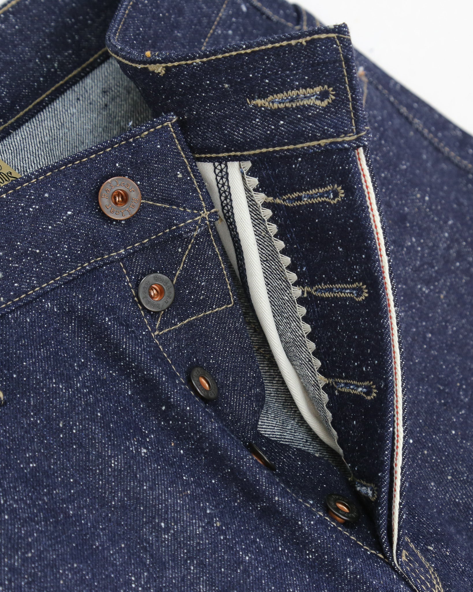 Close-up of X125 Super Nep denim button fly with with focus on stitching and buttons on a white background