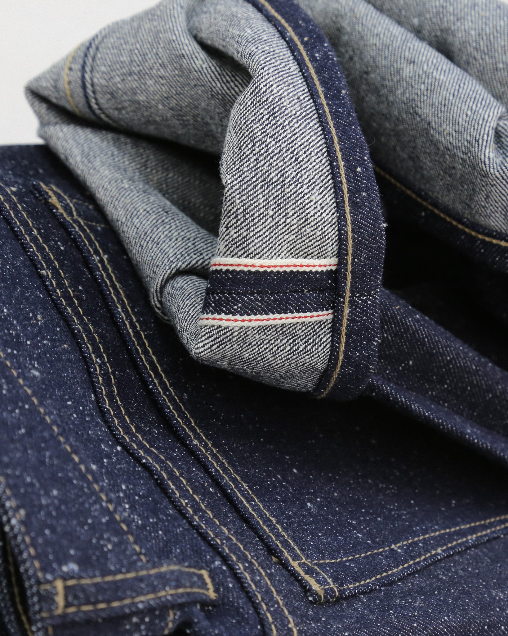 Close-up of blue denim fabric with a focus on stitching and texture.