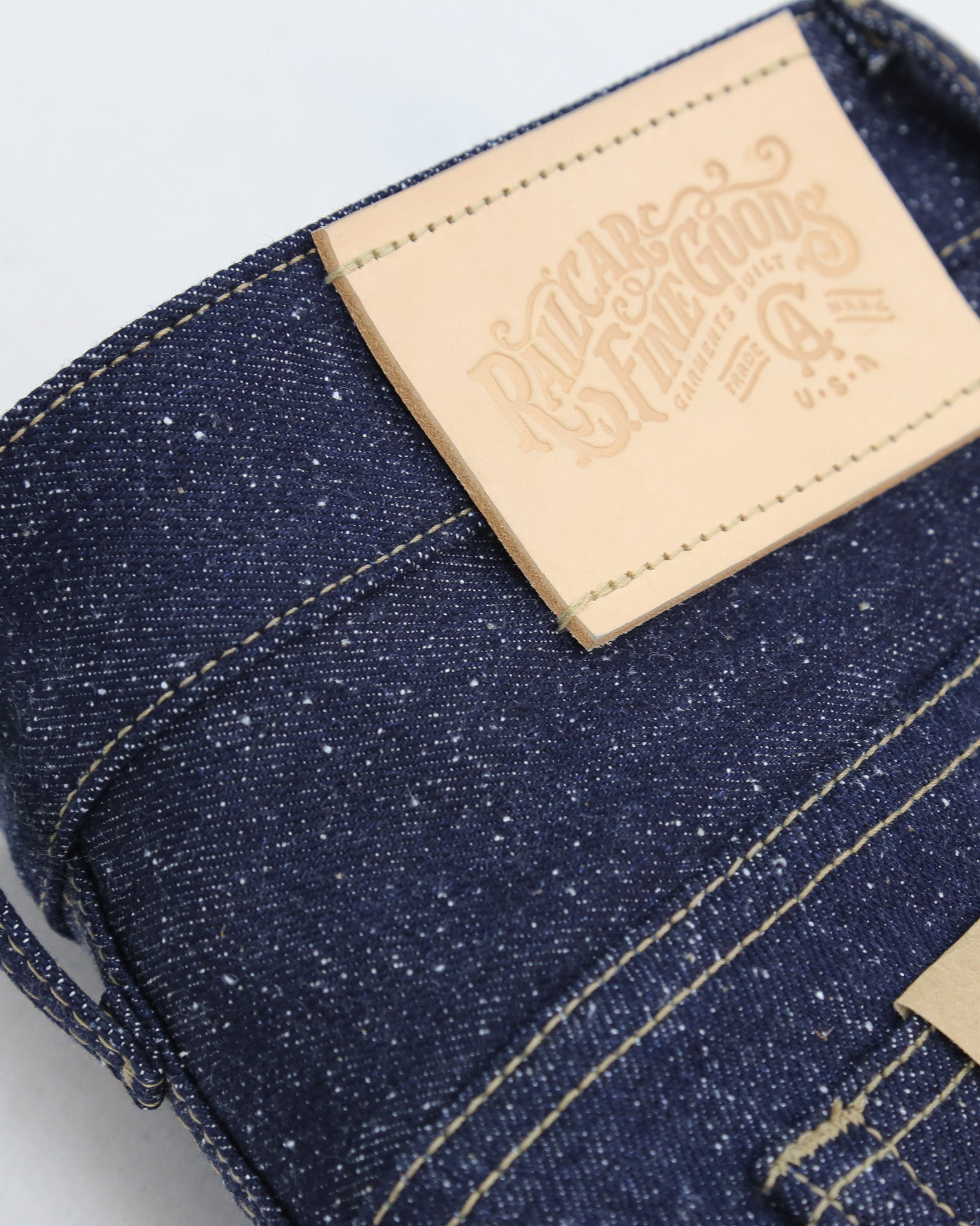 Close-up of X125 Super Nep denim fabric with a leather label on a light gray background