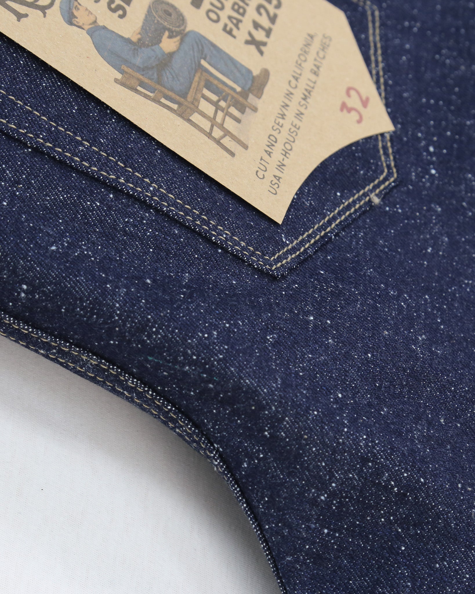 Close-up of X125 Super Nep denim fabric with a tag on a white background